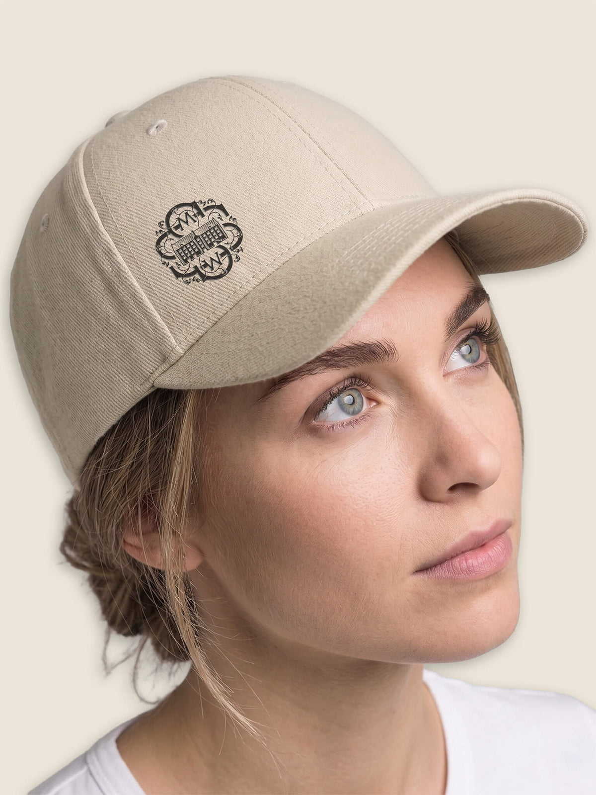 Woman wearing a stone Scottish Malt Whisky Society baseball cap with black logo on the front right panel.