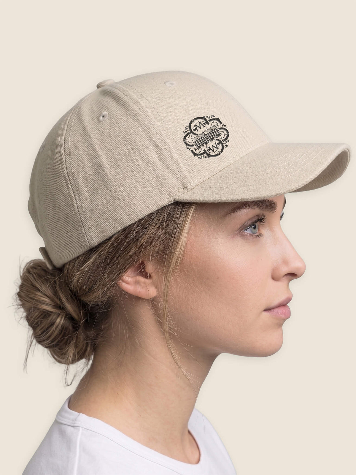 Side view of woman wearing a stone Scottish Malt Whisky Society baseball cap with black logo on the front right panel.
