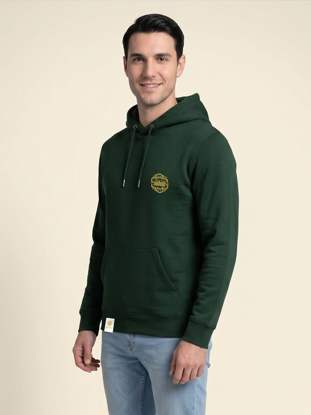 Side view of a man wearing a forest green Scottish Malt Whisky Society hoodie with gold logo on the left chest.