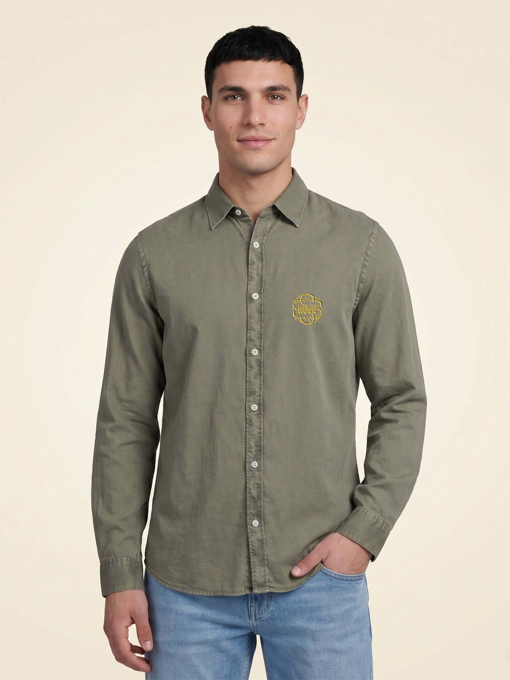 Man wearing a washed pale khaki organic cotton shirt with SMWS logo mark on left chest.