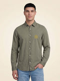 Man wearing a washed pale khaki organic cotton shirt with SMWS logo mark on left chest.