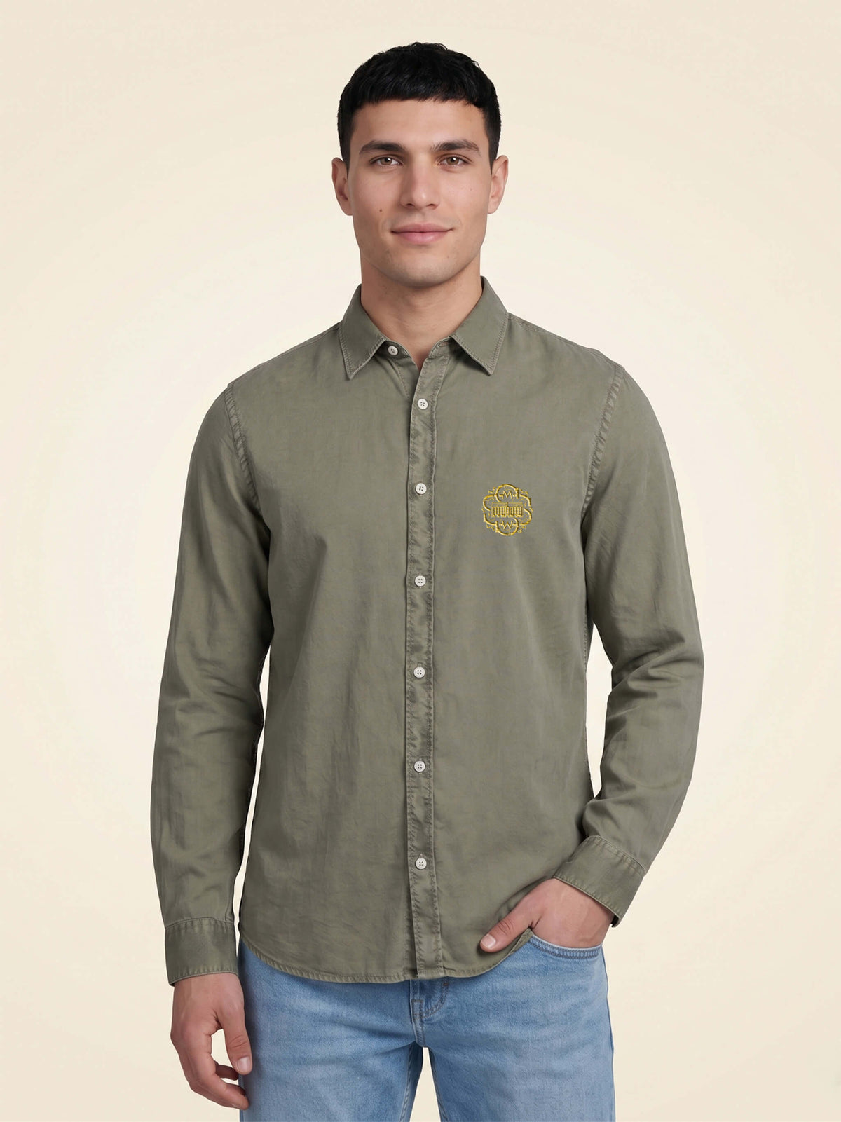 Man wearing a washed pale khaki organic cotton shirt with SMWS logo mark on left chest.