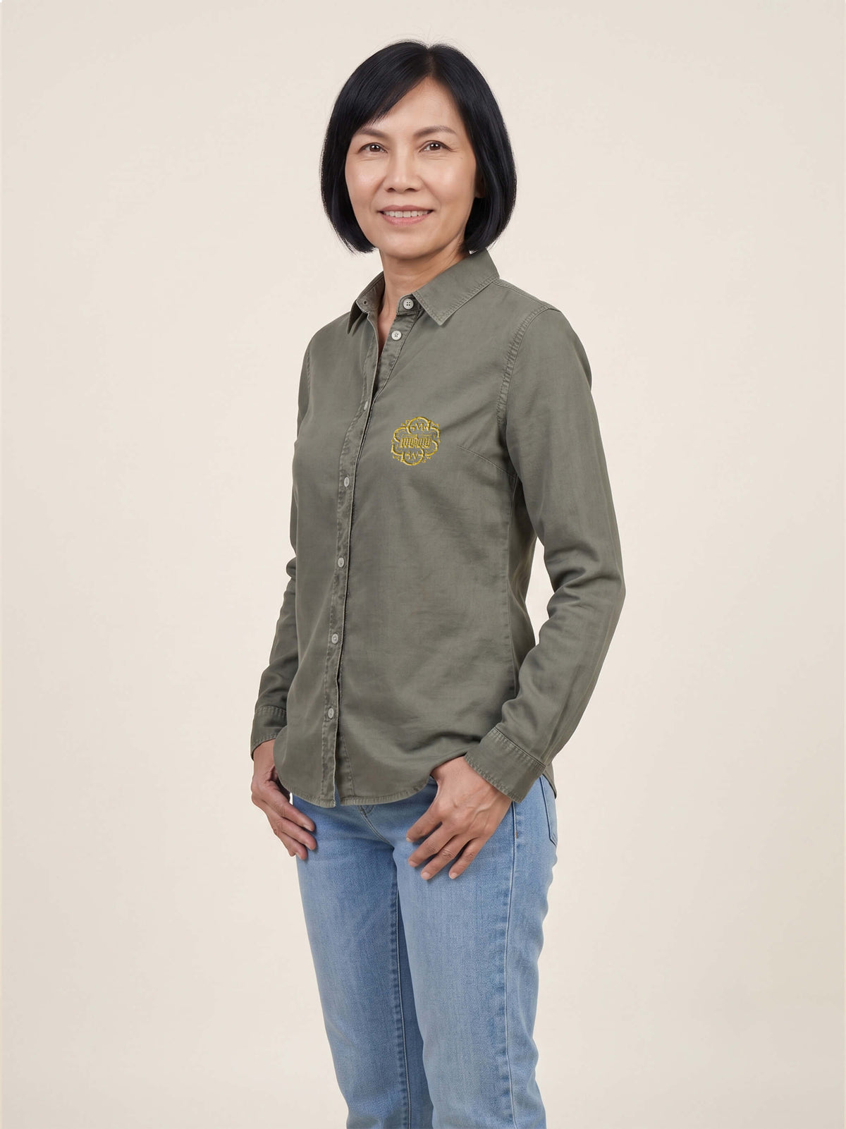 Woman wearing a washed pale khaki Scottish Malt Whisky Society organic shirt with logo on the left chest. Can be personalised with your name on the right chest.