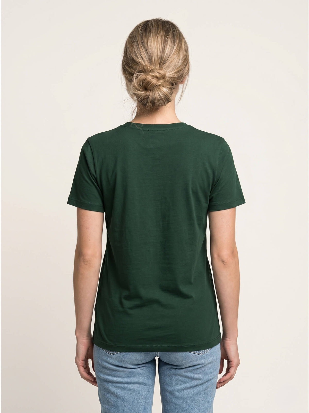 Side view of woman wearing a forest green Scottish Malt Whisky Society t-shirt.