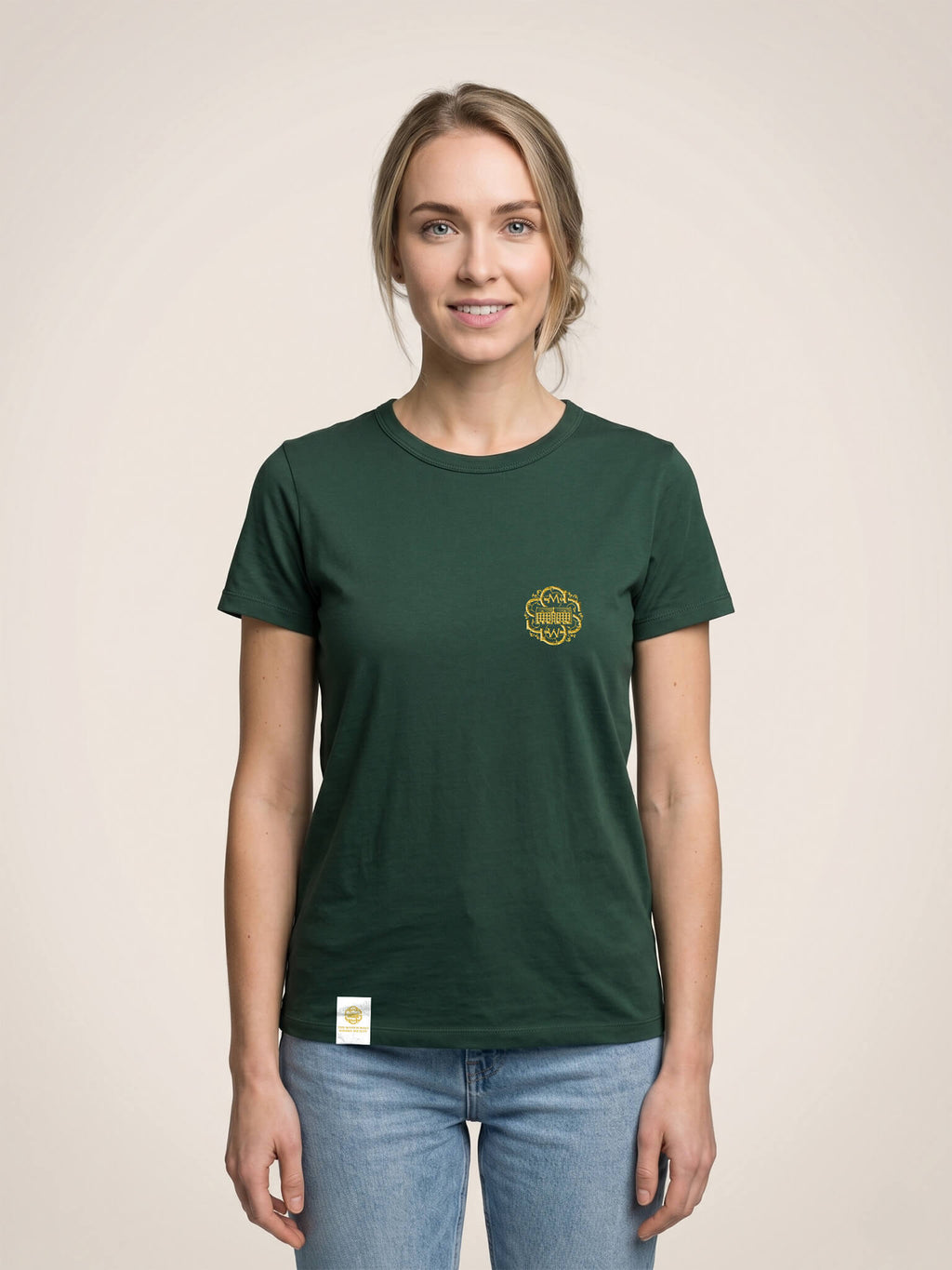 Woman wearing a forest green Scottish Malt Whisky Society t-shirt with gold logo on the left chest.