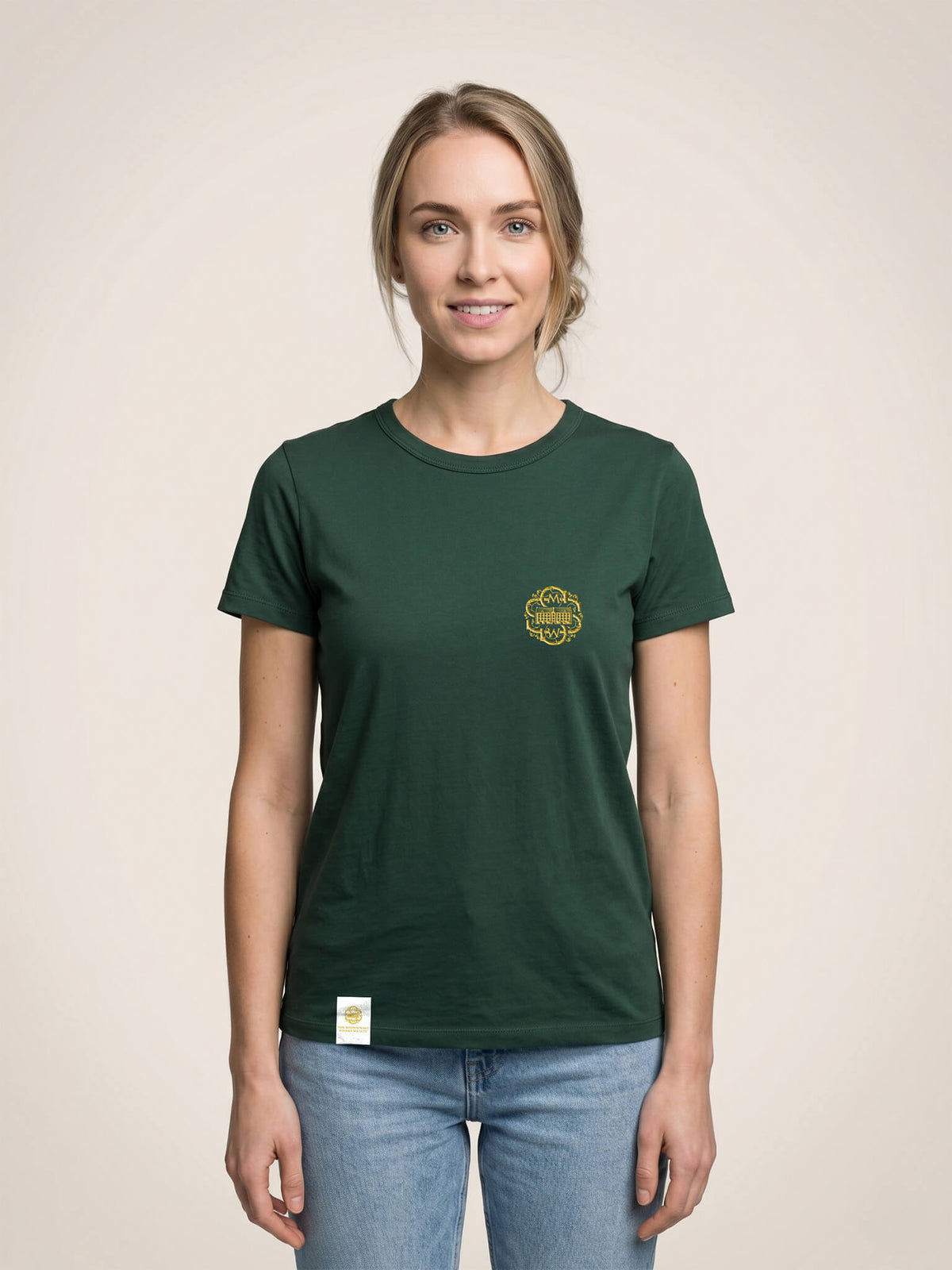 Woman wearing a forest green Scottish Malt Whisky Society t-shirt with gold logo on the left chest.